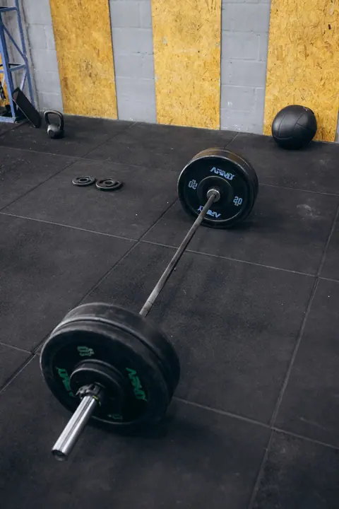 Loaded barbell resting on rubber gym flooring